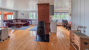 A spacious living room with a fireplace, a dining area, and a kitchen in the background. - Amazing home in ørje with house sea view (Ørje)