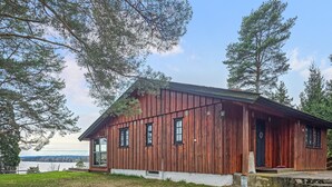 A rustic wooden cabin with a porch, large windows, and a view of a lake. - Amazing home in ørje with house sea view (Ørje)