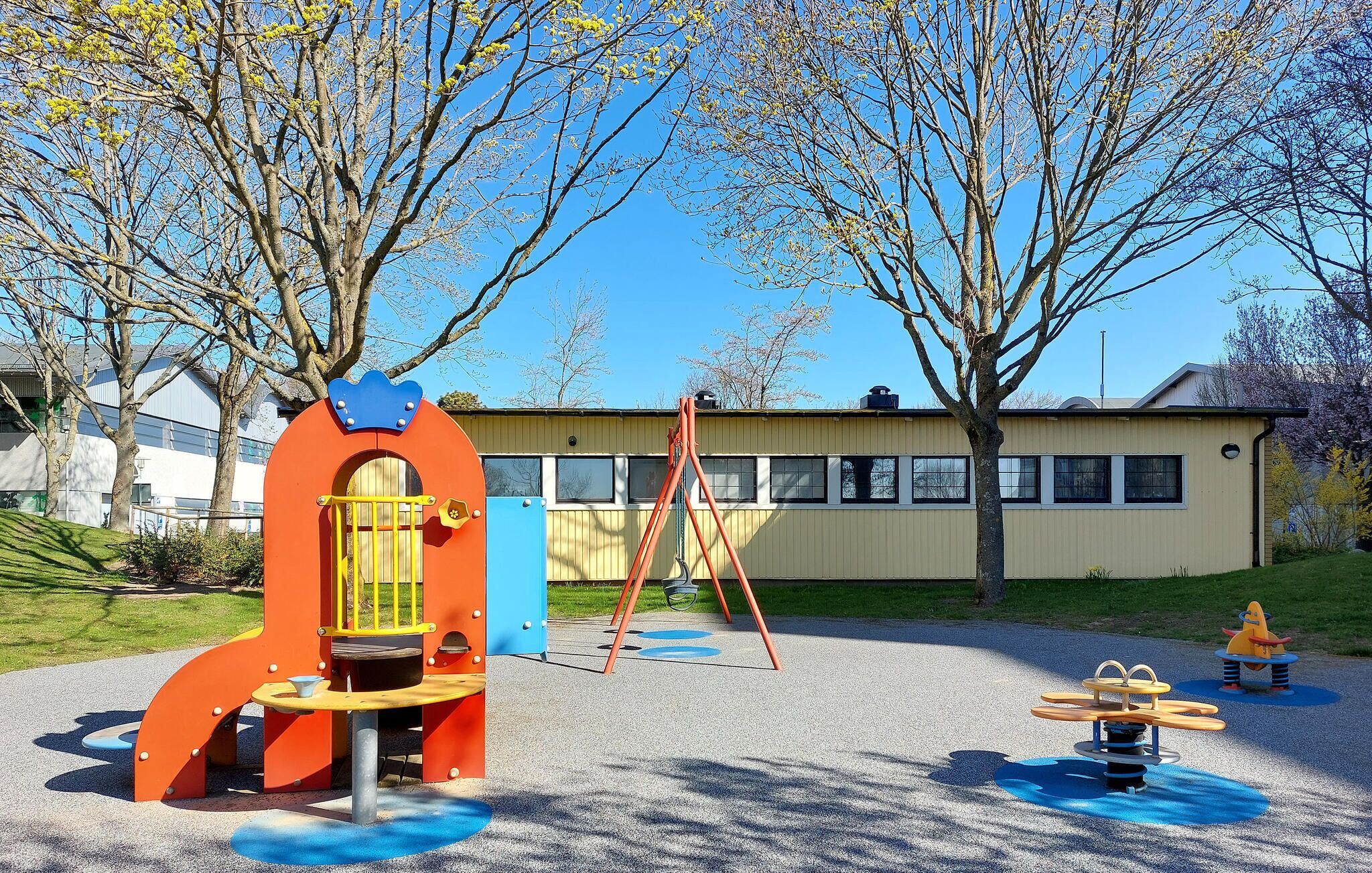 Une aire de jeux avec une structure d’escalade, des balançoires et un toboggan.