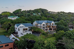 Un moderno complejo residencial con varias casas, paneles solares y abundante vegetación.