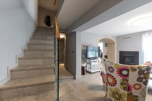 Eine Treppe führt zu einem Wohnbereich mit Fernseher, Kamin und einem bunten Sessel.