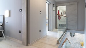Ein modernes Interieur mit einem Flur, der zu einer Glastür, einer Treppe und einer Außenansicht führt.