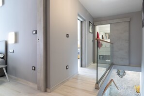 Ein modernes Interieur mit einem Flur, der zu einer Glastür, einer Treppe und einer Außenansicht führt.