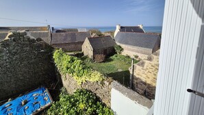 Un village côtier aux bâtiments en pierre, avec un ciel dégagé et la mer en toile de fond.
