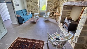 Un salon avec un mur en pierre, une cheminée, un canapé, une petite table et un tapis à motifs.
