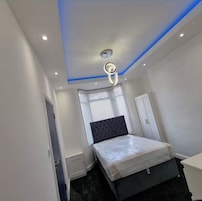 A bedroom with a bed, a window with blinds, a door, and a ceiling light fixture.