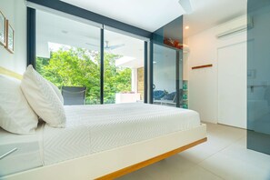 A modern bedroom with a bed, a sliding glass door leading to a balcony, and a built-in wardrobe.