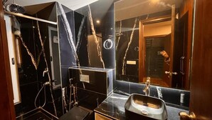 Un baño con tocador de mármol negro, lavamanos y espejo.