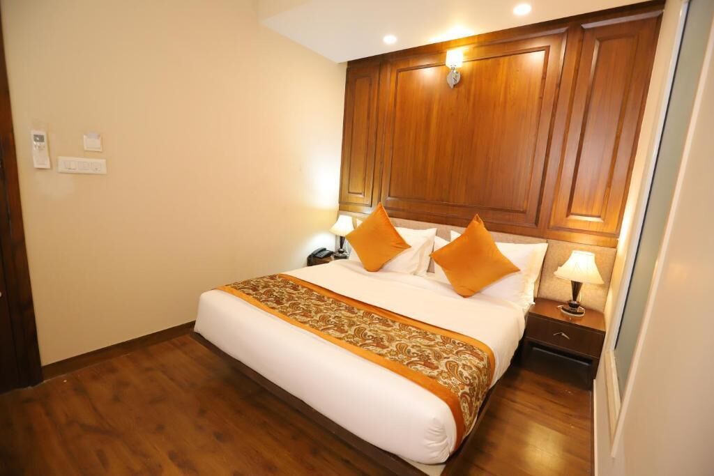A hotel room with a large bed, wooden headboard, two bedside tables with lamps, and a wooden floor.