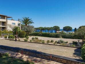Ein Küsteneigentum mit gepflastertem Bereich, einer Palme und Blick auf das Meer.