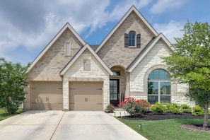 A two-story house with a stone facade, two garage doors, and a large arched window. - 10 Min from Austin! High-End Home w/ nice backyard (Manor)