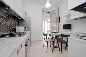 Una cocina compacta con estufa a gas, microondas y muebles de cocina modernos.