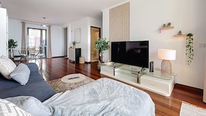 Ett modernt vardagsrum med en soffa, en tv och en matplats med stolar och ett bord.