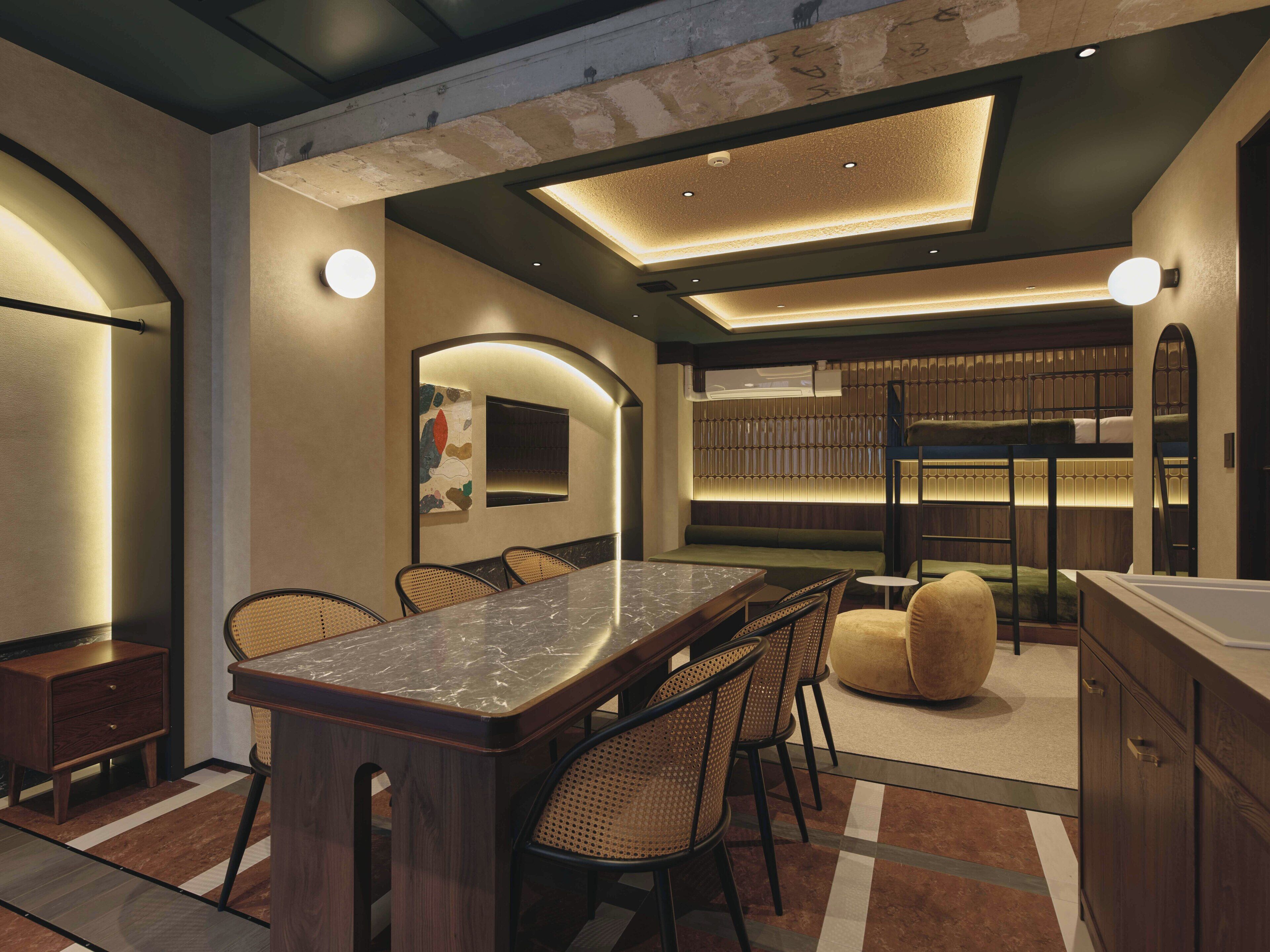 A modern dining area with a marble table, wicker chairs, and a cozy seating area with a round ottoman.
