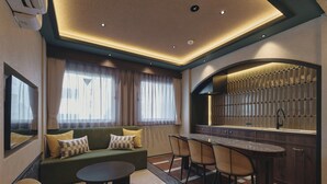 Una habitación de hotel moderna con sofá, una mesa redonda, una zona de bar y un área de descanso.