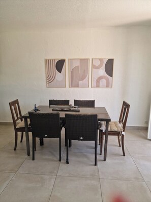 A dining area with a rectangular table, six chairs, and three abstract wall art pieces.