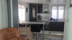 Une cuisine moderne avec un coin repas, un fauteuil en cuir marron et un tabouret de bar.