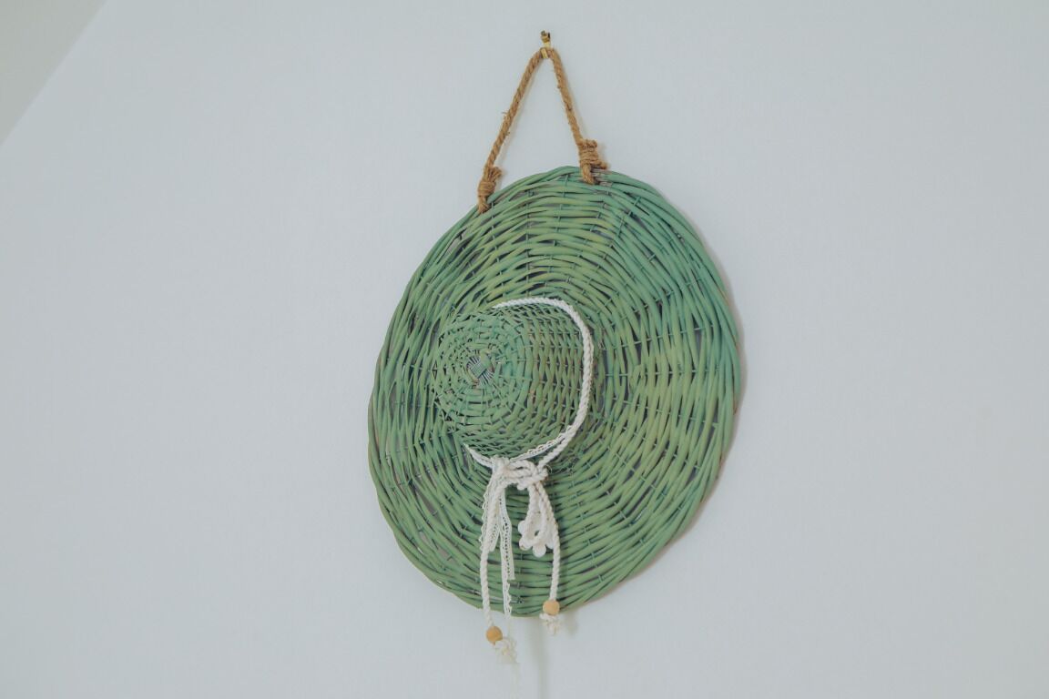 A circular woven wall hanging with a central knot and tassels.