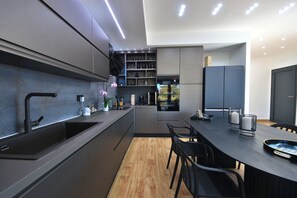 A modern kitchen with a built-in oven, a sink, and a dining area with a table and chairs.