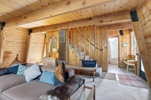 Ein Holzinterieur mit einer Couch, Kissen, einer Bank, einer Tasche und einer Treppe.