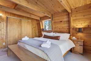 Ein Zimmer in einer Holzhütte mit Bett, Bank, Nachttisch, Lampe und Fenster.