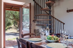 A dining table with plates, glasses, and a bottle of wine, set against a staircase and a view of trees. - HYDROMASSAGE BATHTUB-AGRITURISMO FATTORIA LA PIEVE-COTTAGE OLIVO 8 km from Pisa (calci)