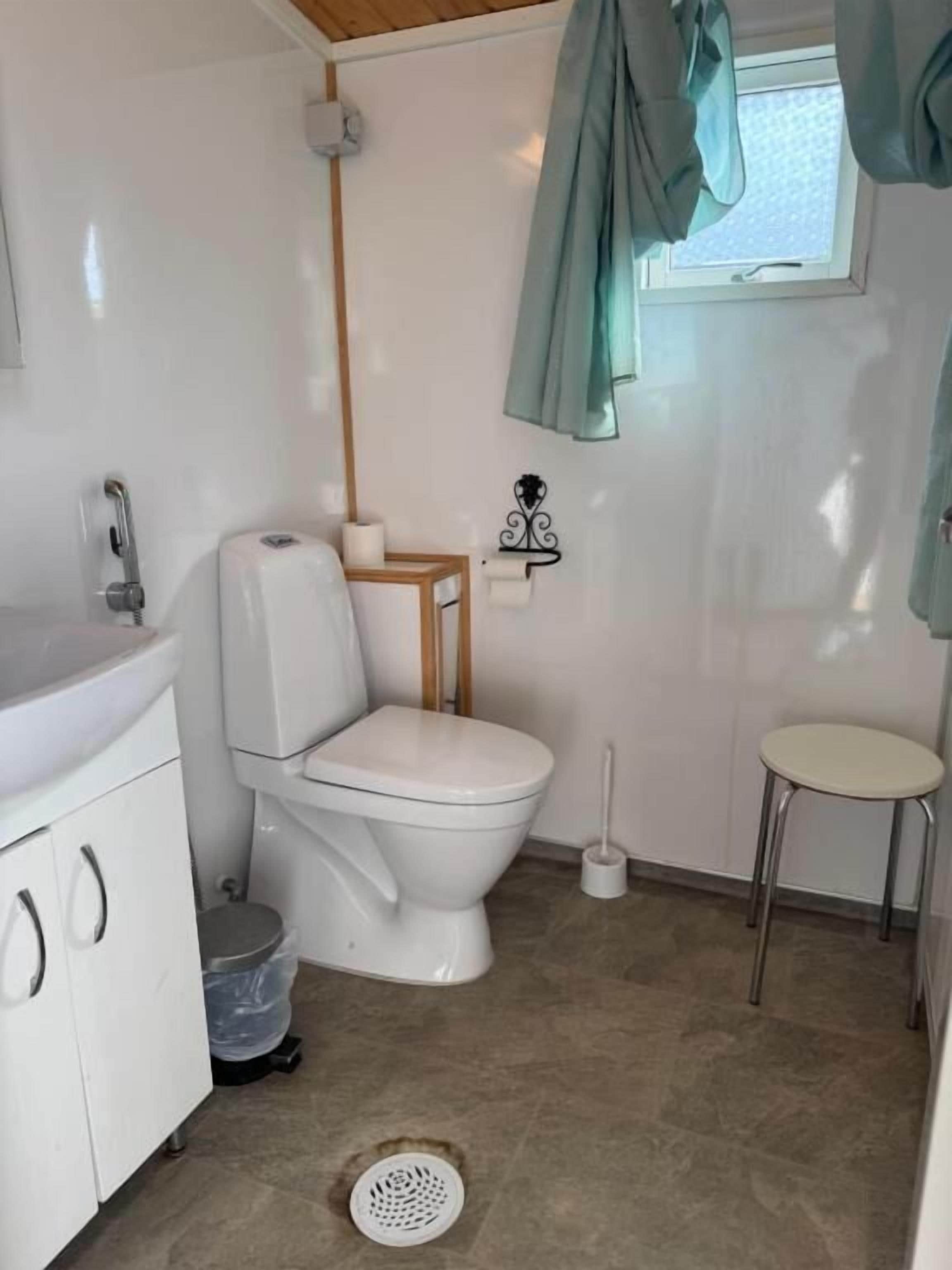 Een kleine badkamer met toilet, wastafel en een klein krukje.
