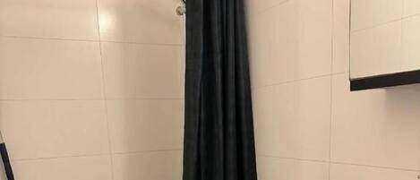 Un baño con inodoro, cortina de ducha, escoba y lavabo.