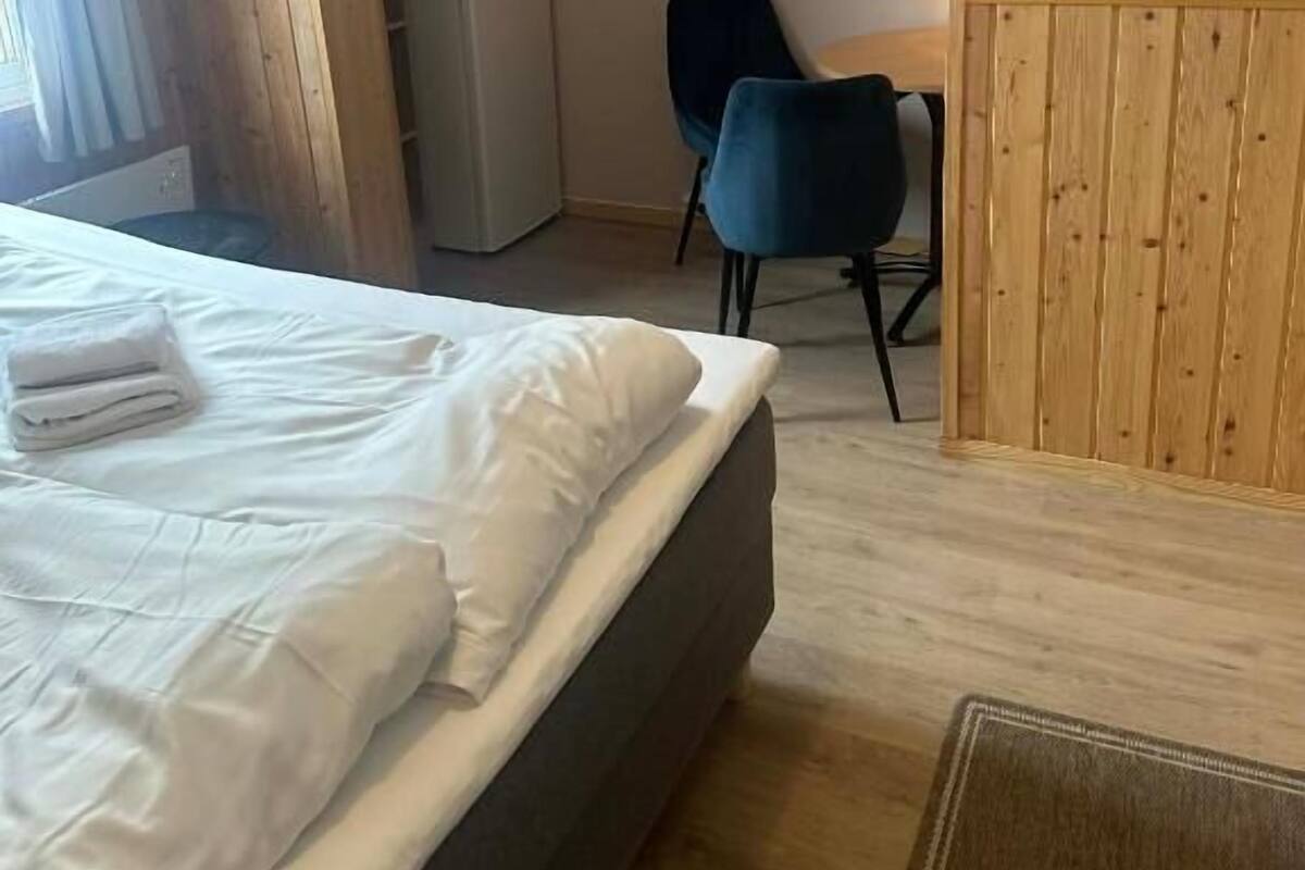 Habitació d'hotel amb llit, escriptori, cadira, nevera i un element decoratiu circular penjat a la paret.