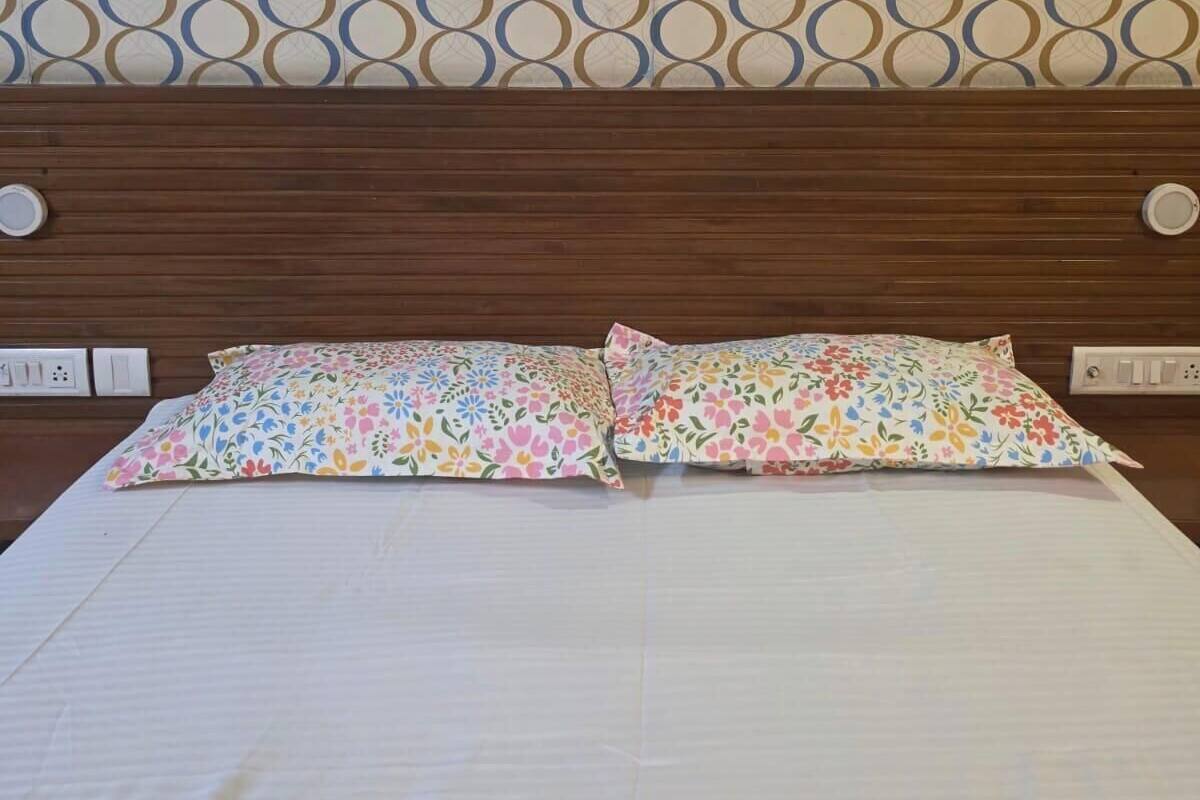 A bed with floral-patterned pillows, a wooden headboard, and a patterned wall.