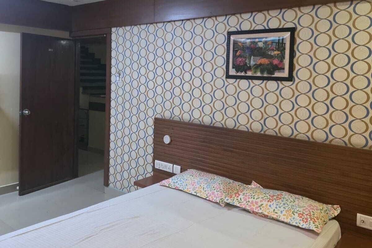 A bedroom with a bed, a ceiling fan, a patterned wall, and a door leading to another room.