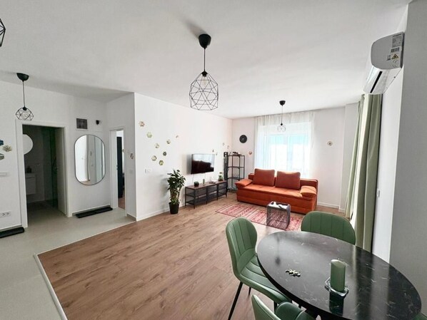 A modern living room with a sofa, a TV, and a dining area with a table and chairs. - Soulful Apartment Mara M11 (Timișoara)