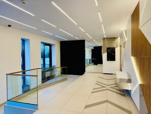 Un interno moderno con ringhiera in vetro, pavimento a motivi geometrici e illuminazione a incasso.