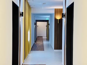 Modernilla designilla sisustettu hotellin käytävä, jossa on keskeinen käytävä, ovet molemmin puolin ja selvästi näkyvä opaste uloskäyntiin.