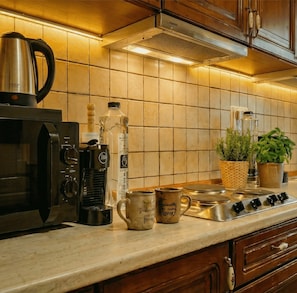 A kitchen with a coffee maker, a kettle, a bottle, and a mug on the counter. - Modern Luxury Suite with Panoramic City Views (Timișoara)