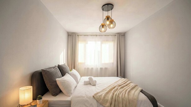 A modern bedroom with a bed, bedside lamp, and a hanging light fixture. - Joy City Stay Pavel Rotariu 19 (Timișoara)