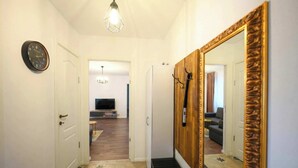 A hallway with a large mirror, a clock, and a staircase leading to another room. - Joy City Stay Pavel Rotariu 19 (Timișoara)