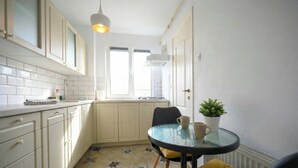 A kitchen with white cabinets, a round glass table, and a potted plant. - Joy City Stay Pavel Rotariu 19 (Timișoara)