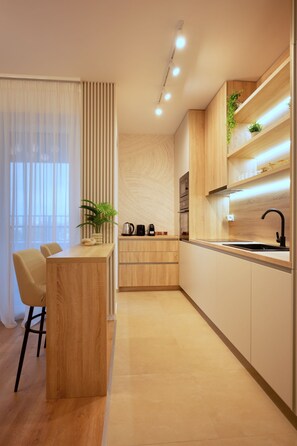 A modern kitchen with wooden cabinets, a central island, and a dining area with chairs. - Joy City Stay | City of Mara M11-61 (Timișoara)