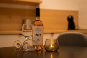 Een fles wijn, een glas en een kaars op een tafel.