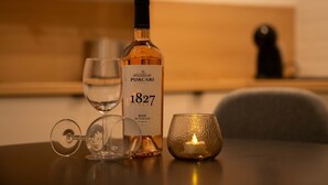 Una botella de vino, una copa y una vela sobre una mesa.