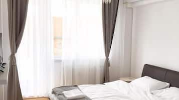 Un dormitorio moderno con una cama de madera, ropa de cama blanca, una araña y un equipo de aire acondicionado.