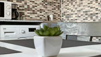 Una cocina con microondas, cafetera y una planta en maceta sobre la encimera.