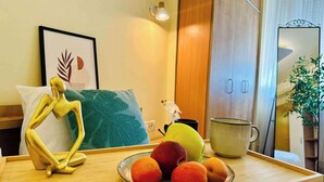 A wooden table with a plate of fruit, a decorative golden figure, a framed artwork, and a mirror. - Joy City Stay Ultracentral Charming (Timișoara)