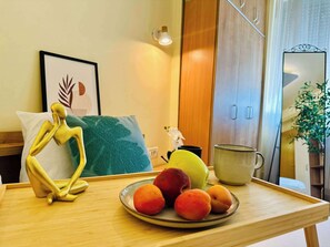 Ein Holztisch mit einer Fruchtschale, einer verzierten goldenen Figur, einem gerahmten Kunstwerk und einem Spiegel.
