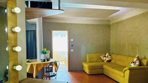 A living room with a wooden table, a yellow sofa, and a mirror with lights. - Joy City Stay Ultracentral Charming (Timișoara)