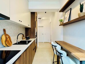 A modern kitchen with wooden cabinets, a marble countertop, a built-in oven, and a dining area with a wooden table and bar stools. - Joy City Stay M11-81 (Timișoara)