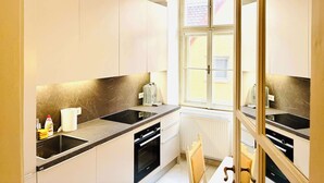 Een moderne keuken met een zwart aanrecht, witte kasten, een raam en een radiator.
