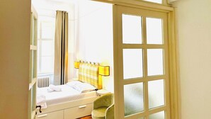 Een slaapkamer met een bed, een stoel, een raam en een deur.