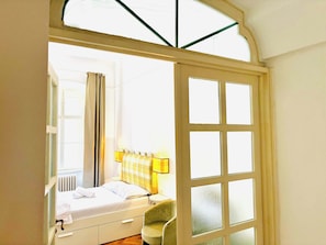 Une chambre à coucher avec un lit, une chaise, une fenêtre et une porte.